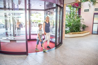 Ingang ziekenhuis Jongen en moeder lopen binnen bij de ingang van het ziekenhuis