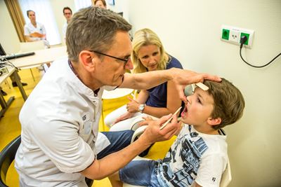De orthodontist De orthodontist kijkt in de mond van de patiënt