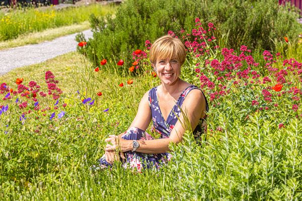 Marita van Polen is arbeid- en organisatiedeskundige Marita van Polen zittend tussen de veldbloemen