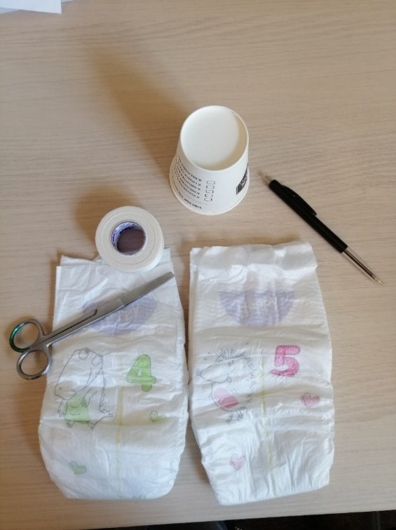 Luiers met schaar, tape, beker en pen
